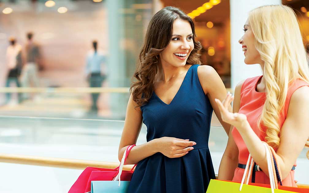 Two women laughing together as they shop at mall