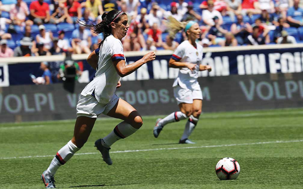 Female soccer players kicking ball down the field