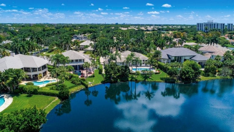 Aerial view of Boca West single-family homes on a lake with Akoya in the background