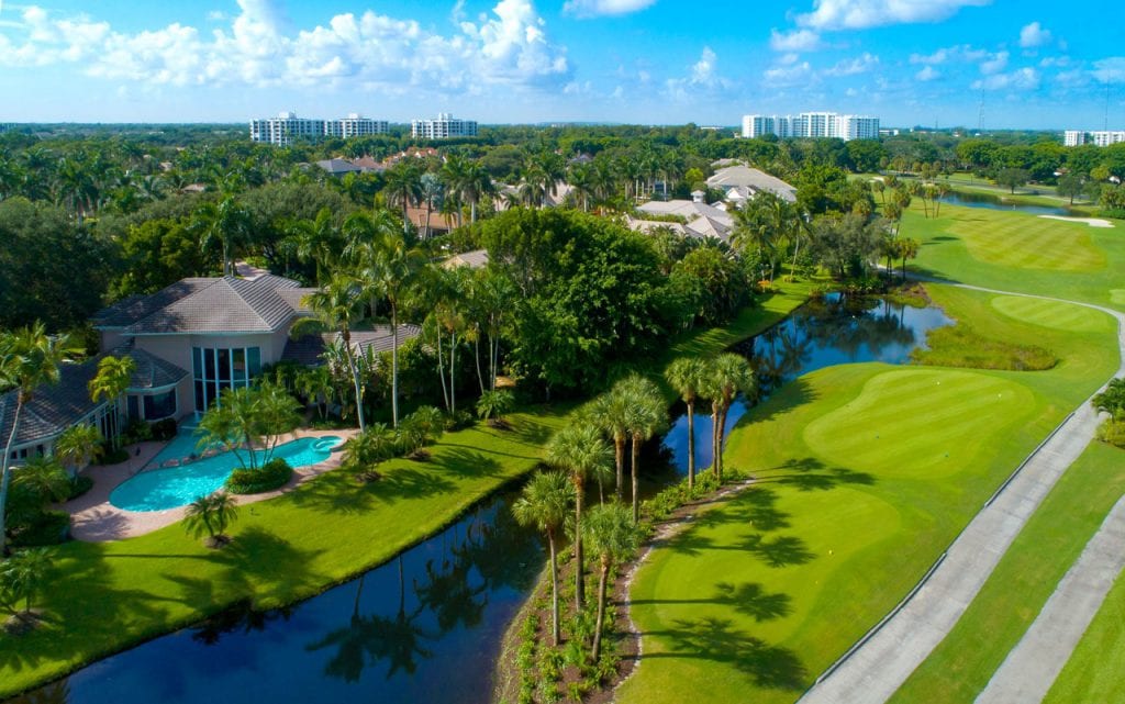 Boca West Home with pool in the backyard next to lake and golf course tee boxes