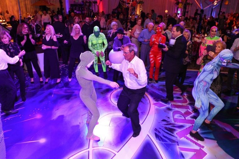 Boca West members dancing with costumed dancers at an event