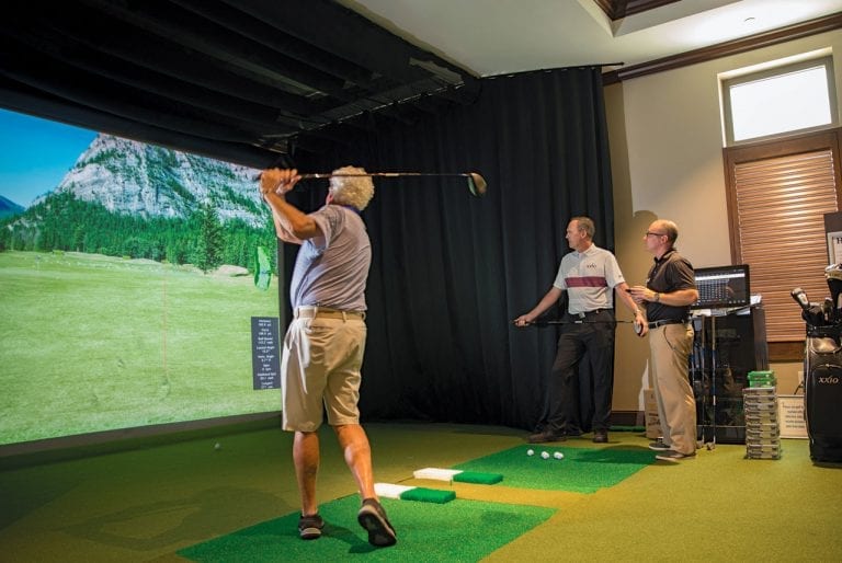 Golfer swinging club on Boca West&#039;s golf simulator during instruction with the PGA Pro