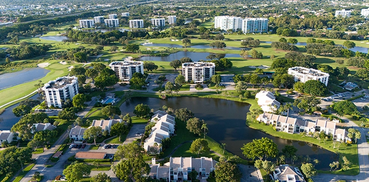 Aerial view of a golf community with buildings, lakes, and fairways