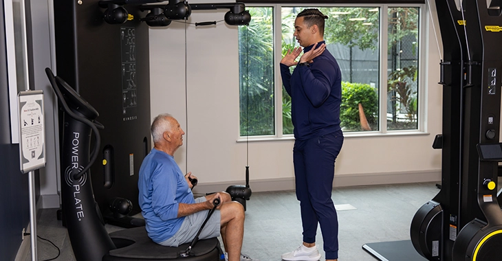 Trainer assisting a member with strength equipment in a fitness center