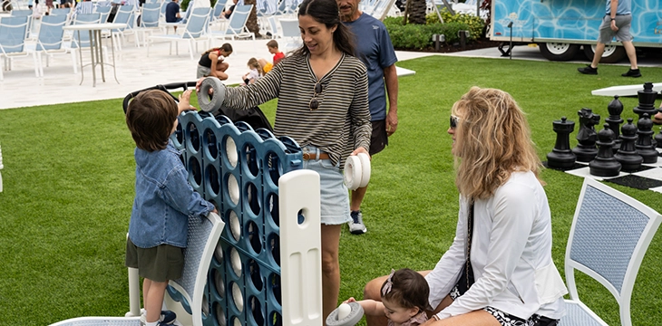 Families and children playing outdoor games on club lawn