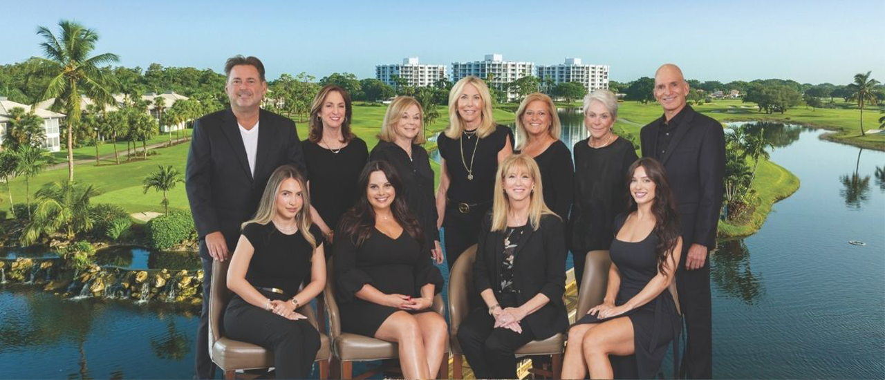 Boca West Realty team posing outdoors with golf course and lake in background