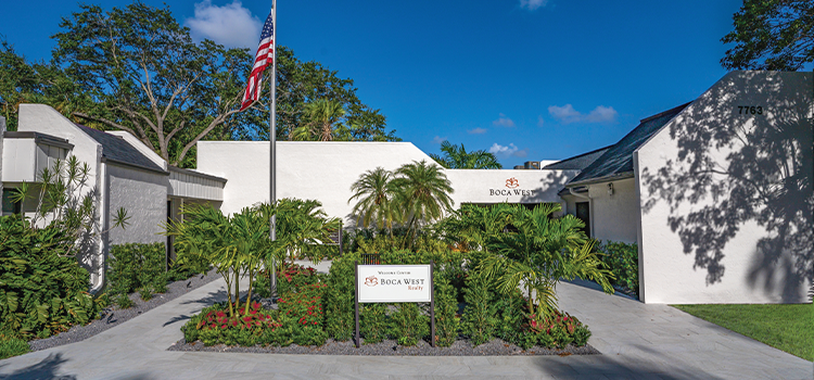 Boca West Realty welcome center exterior with American flag and landscaping