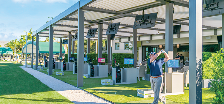Golfer swinging club at covered driving range