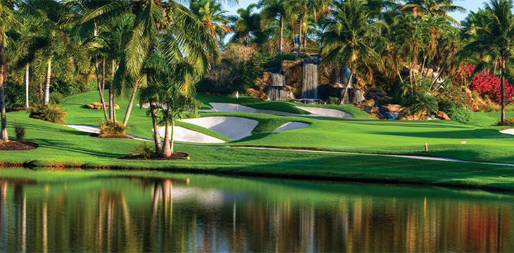 Golf course with palm trees, sand bunkers, and a waterfall