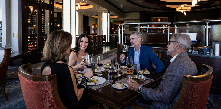 Assorted gourmet dishes plated on white plates against neutral backgrounds.
