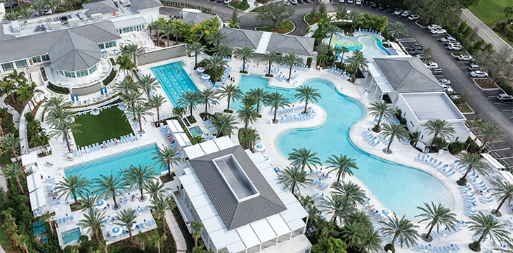 Large resort pool complex with palm trees and lounge chairs