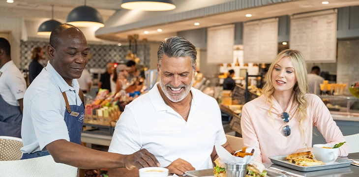 Couple seated at a coffee counter being served lunch.