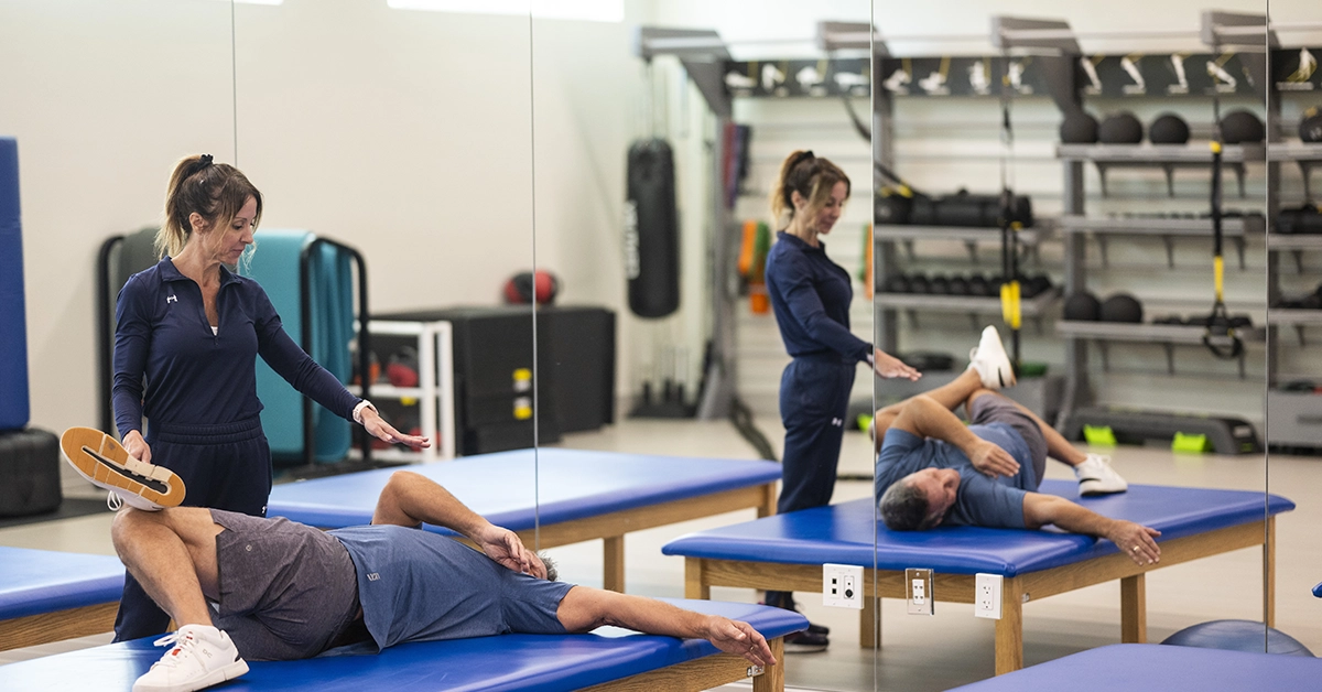 Fitness trainer guiding member through exercise at Boca West Country Club wellness center