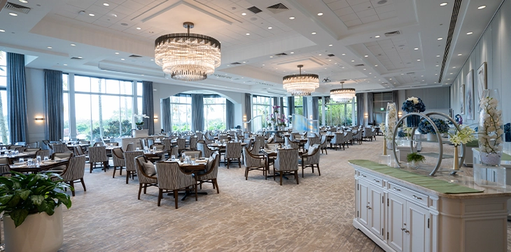 Elegant dining room with chandeliers and tables arranged for guests.