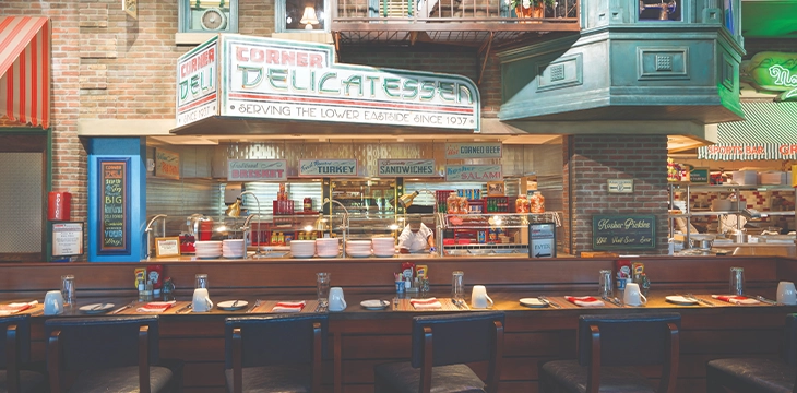 Classic deli counter with stools and sandwich bar signage.