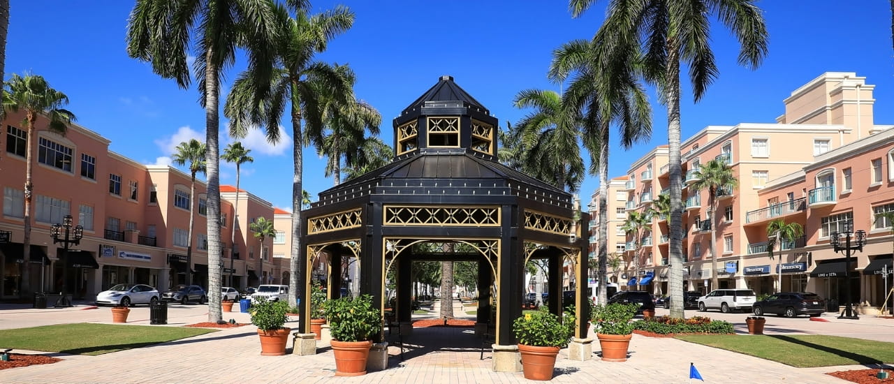 Boca Raton plaza with palm trees, gazebo, shops, and blue sky