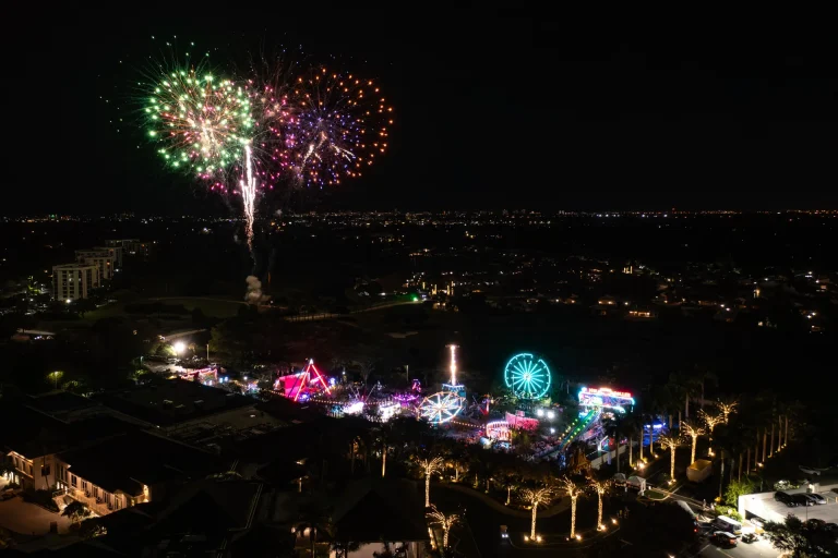 Aerial view of fireworks over the Boca West Fun Fair at night.