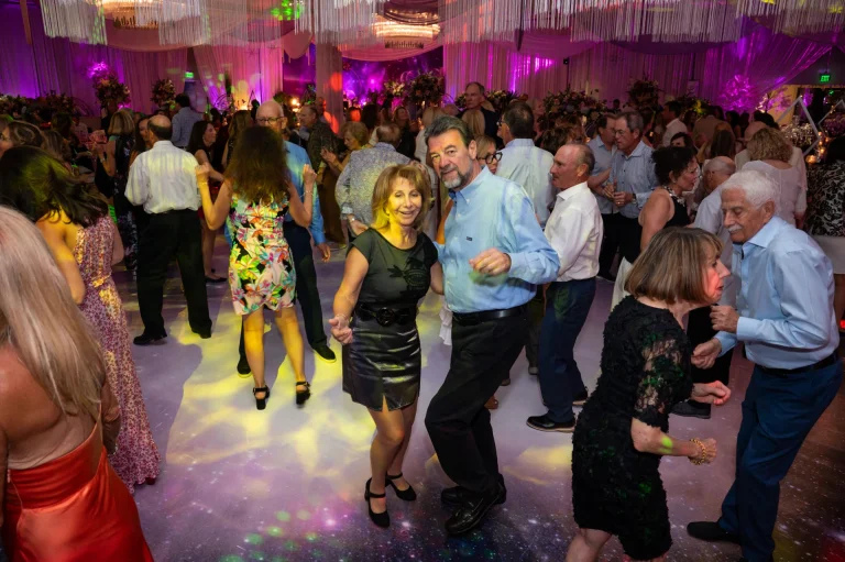 Guests dancing on a lit dance floor at a Boca West evening gala.