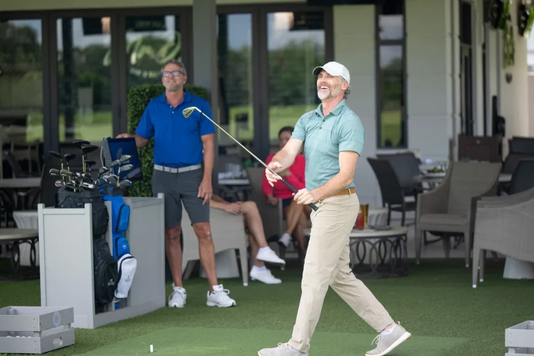 Golfer following through on a swing near the practice bays at Boca West.