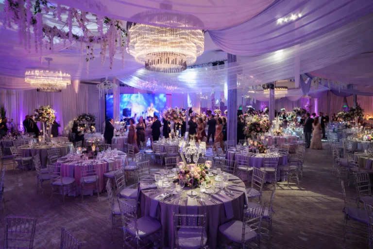 Lavender-draped ballroom with chandeliers and floral garlands set for a Boca West gala.