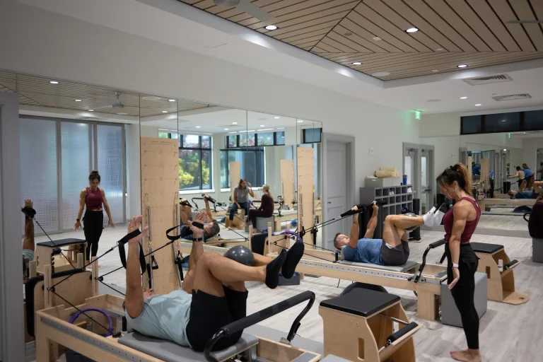 Members on reformer machines during a Pilates class at Boca West with an instructor guiding them.