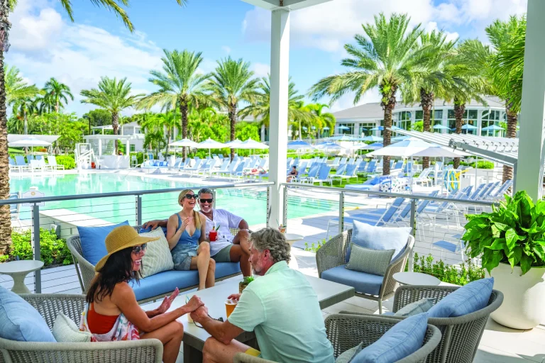 Group of four members relaxing on poolside loungers at Boca West.
