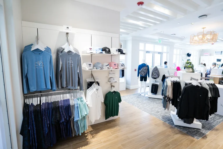 Retail displays of apparel, hats, and bags inside the Boca West pro shop.