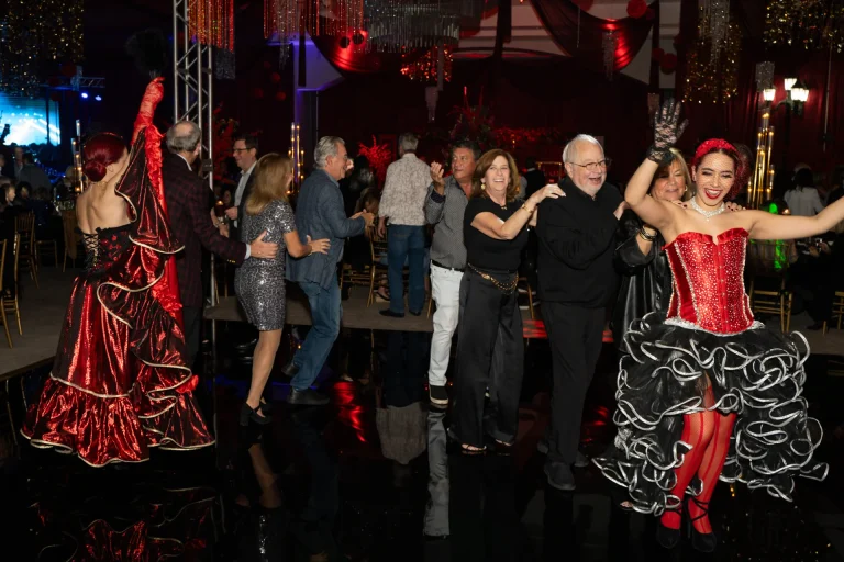 Costumed dancers leading a line of guests dancing at a Boca West themed gala.
