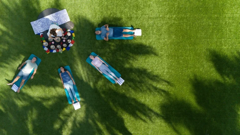 Aerial view of members on mats at a nighttime poolside sound bath event at Boca West.