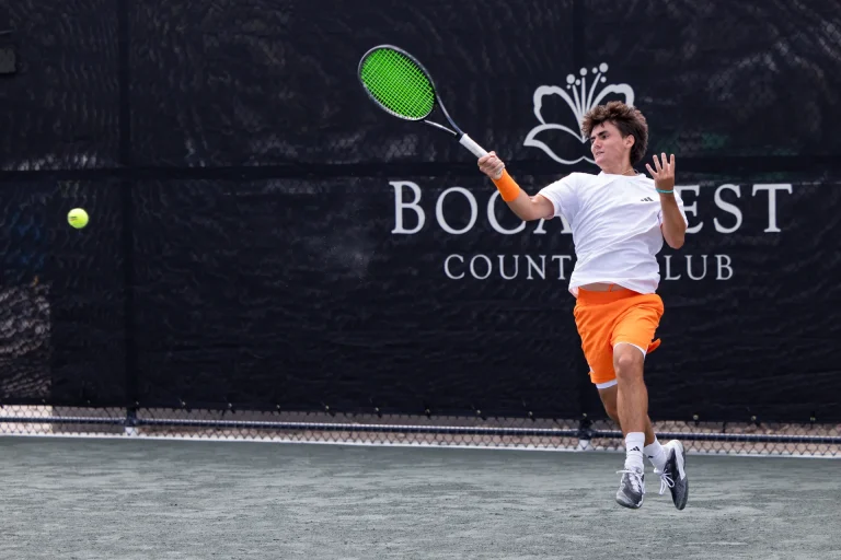 Young tennis player mid-air following through on a forehand at Boca West.